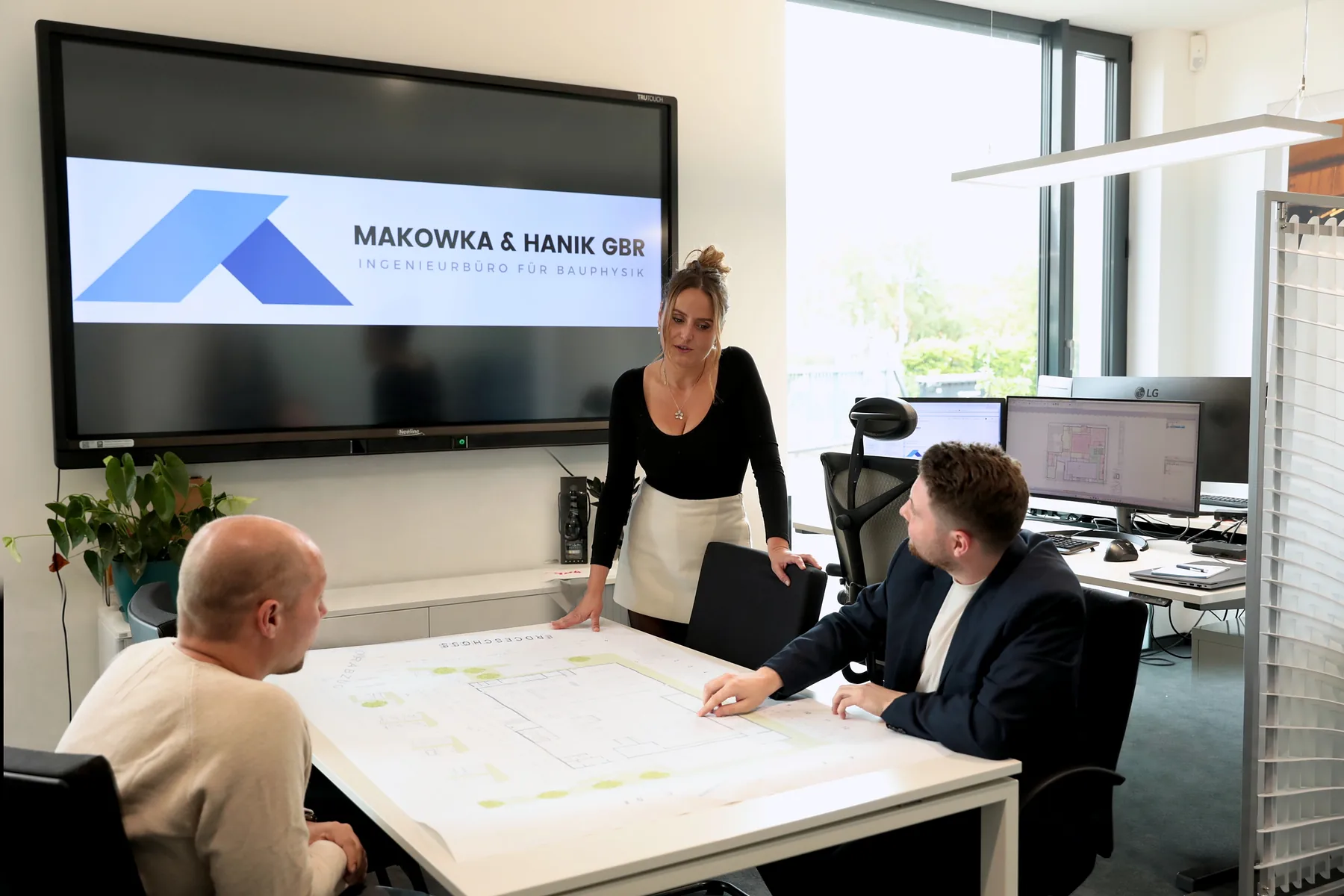 Besprechung am Plantisch - Ingenieurbüro Makowka & Hanik Drei Personen besprechen einen ausgedruckten Grundriss am Plantisch