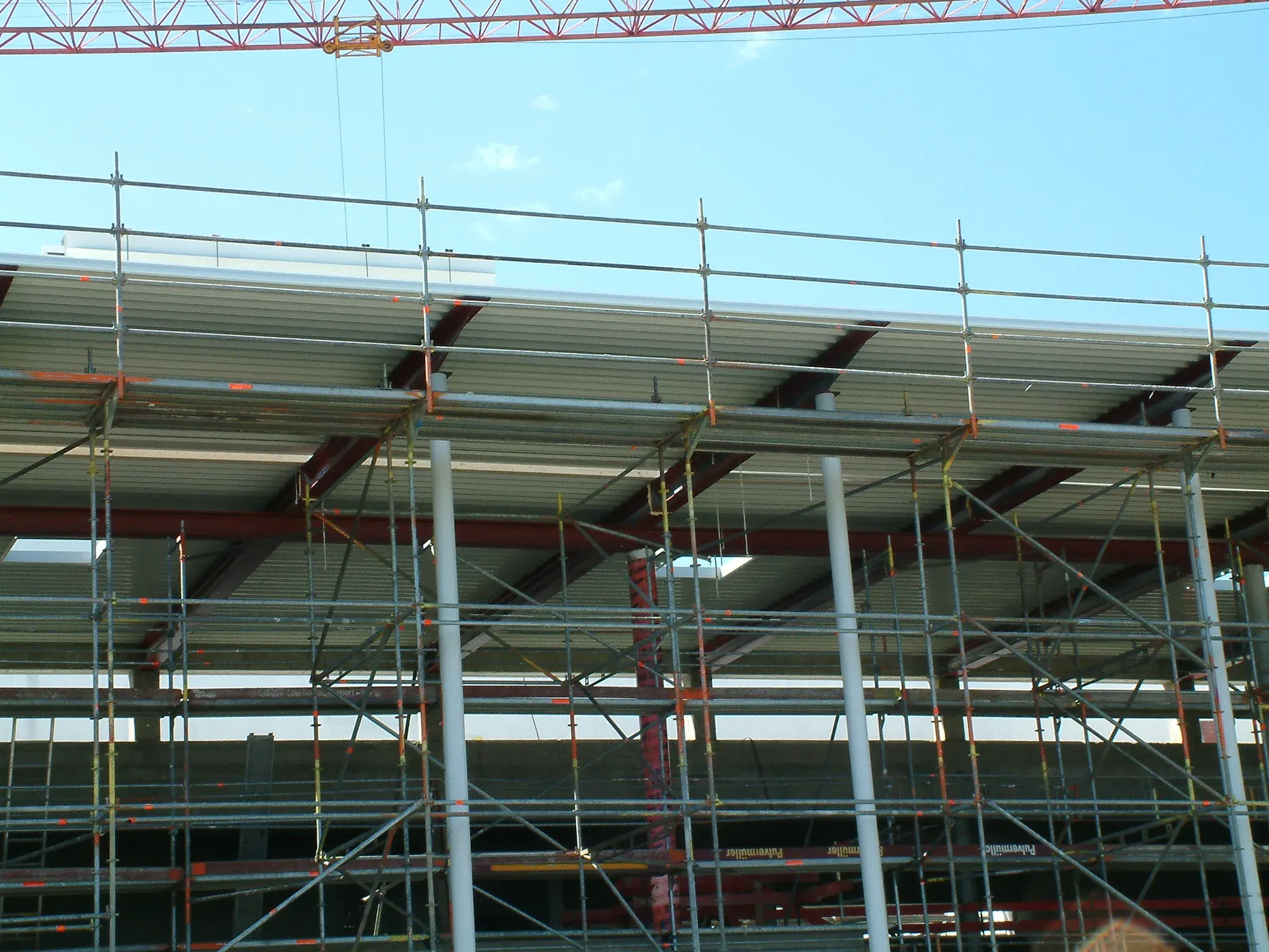Rohbau eines langgestreckten Multiplexgebäudes mit eingerüsteter Fas - Ingenieurbüro Makowka & Hanik Rohbau eines langgestreckten Multiplexgebäudes mit eingerüsteter Fassade und weit auskragendem Vordach vor blauem Himmel